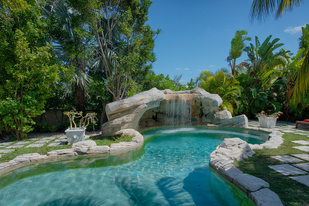 A winding garden path lined with tropical blooms leads up toward a charming stone inn - A Stone's Throw Away